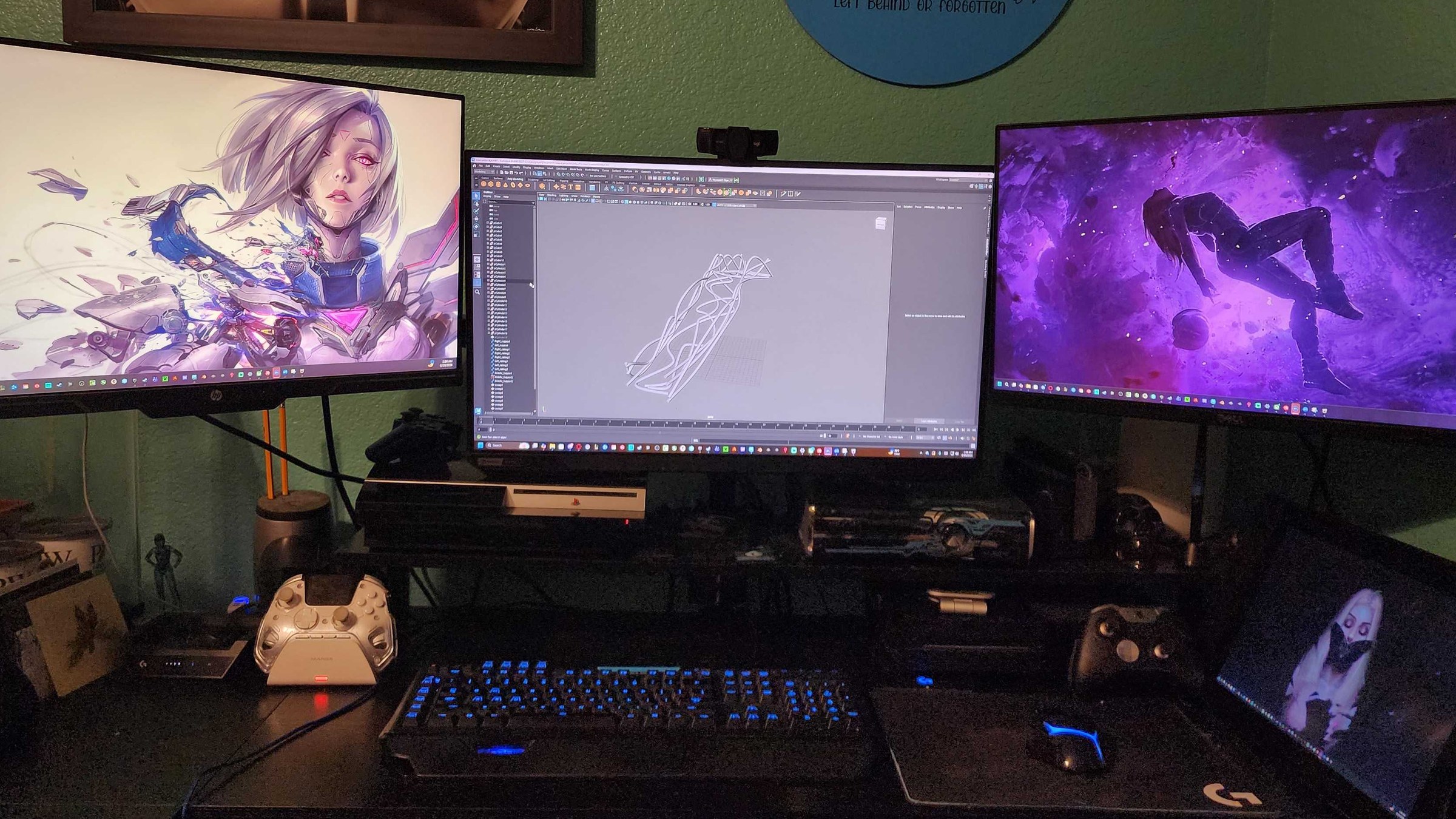 Patrick Byers’ desk: three monitors with 3ds Max open on a prop, a tablet, and controllers.